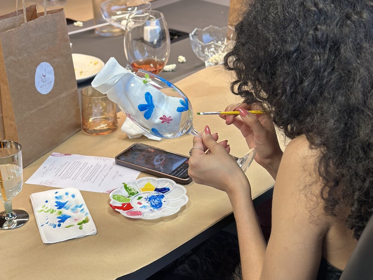 Mãos segurando taças pintadas à mão com flores coloridas