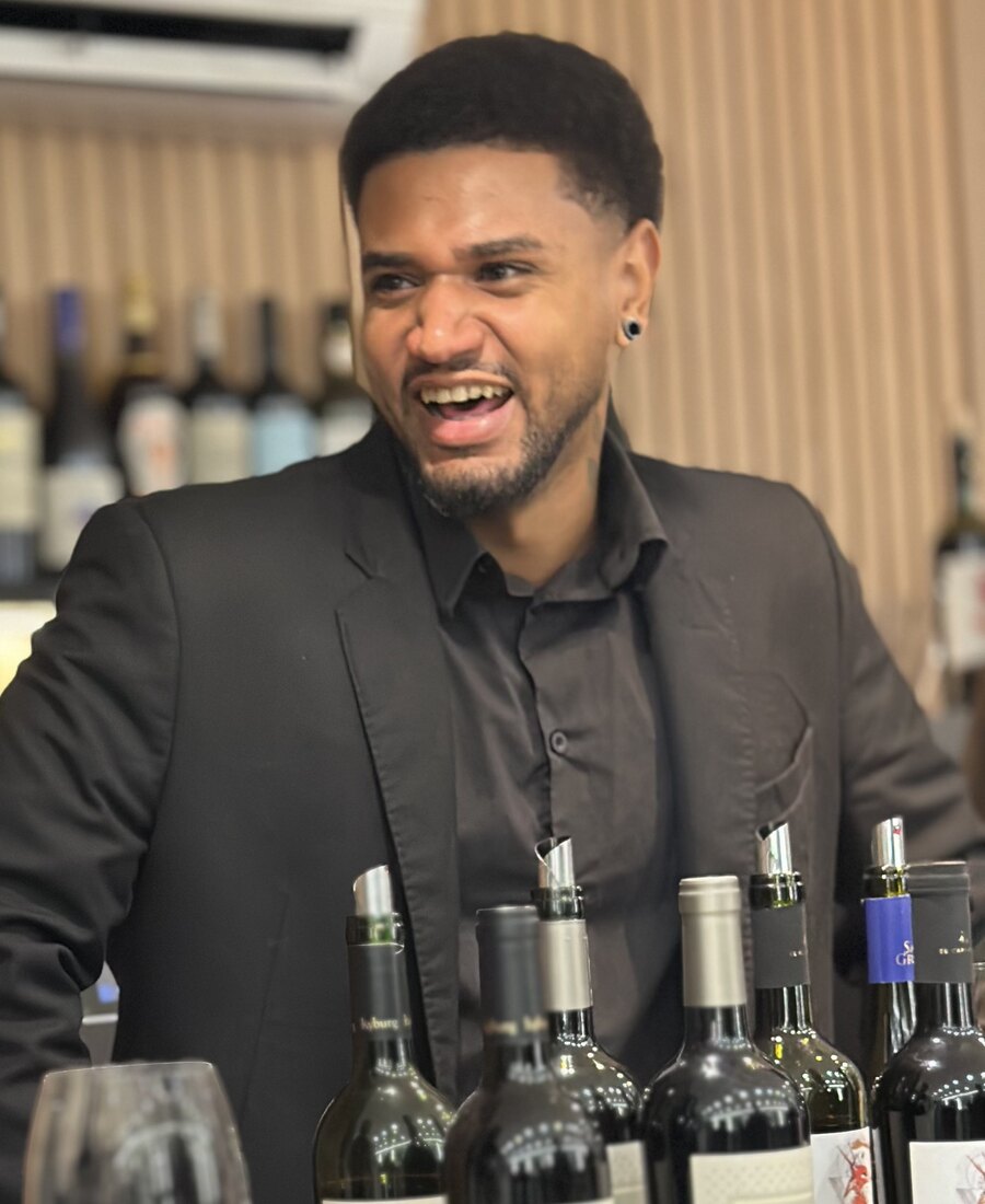 Lucas Borges, sommelier da Tuadega, segurando uma taça de vinho tinto