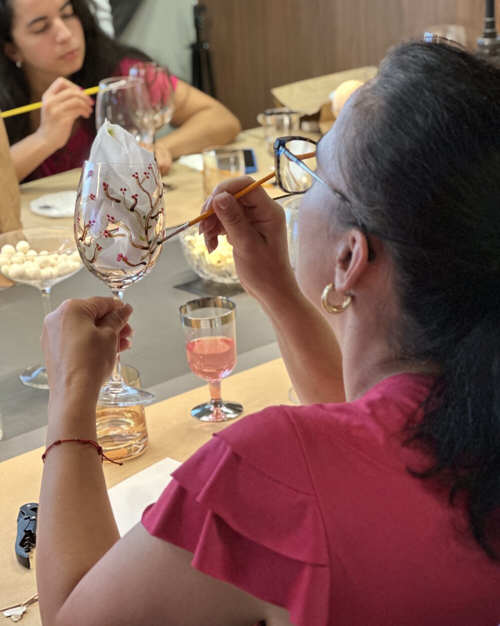 Pessoa pintando uma flor em uma taça de vidro durante o Arte e Taças