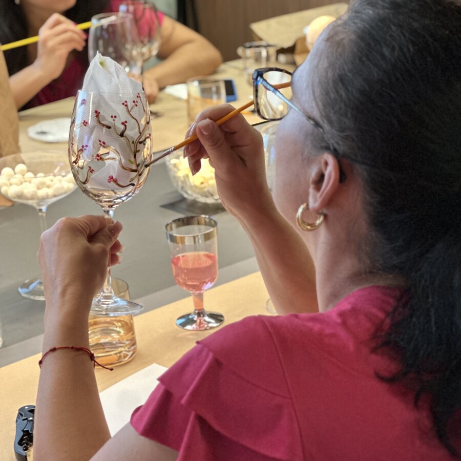Mulher sorrindo enquanto pinta sua taça de vidro